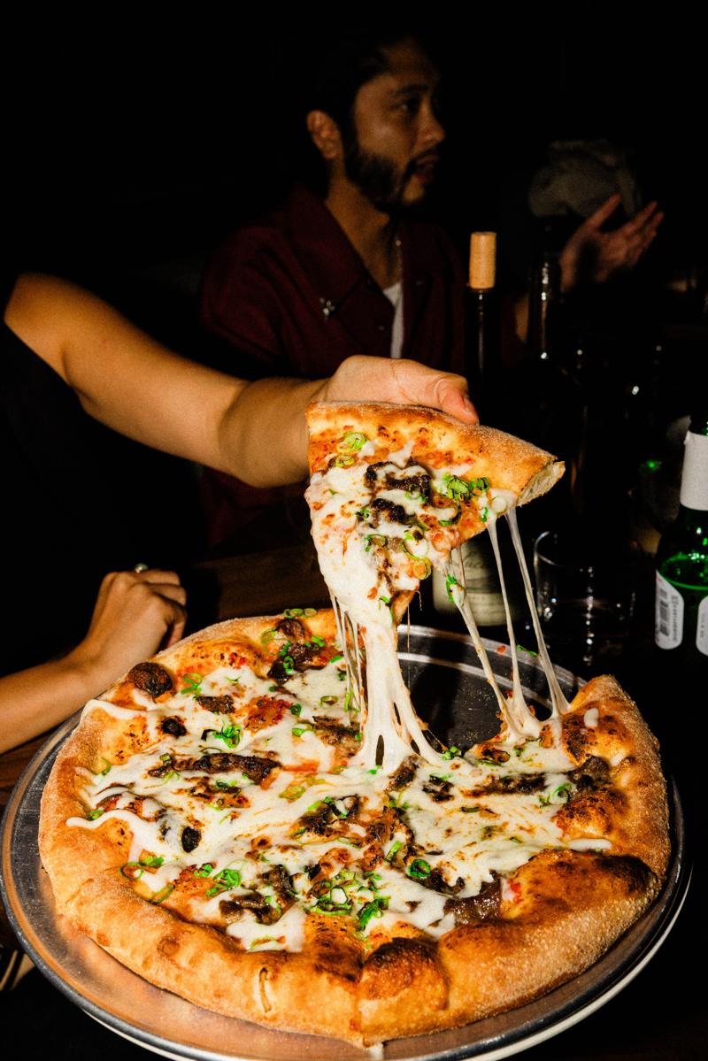 A slice of pizza pulled from the pie with stretching cheese