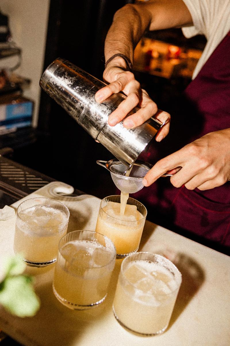 Cocktails being strained into glasses at the bar